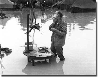 A Marine knee deep in water prepares for a shave on Okinawa